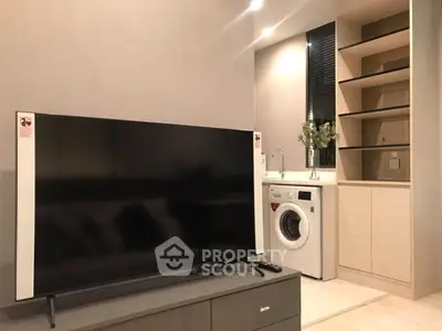 Modern living room with sleek TV and built-in washing machine in stylish apartment.