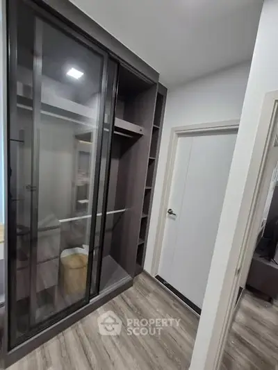 Modern walk-in closet with sleek sliding glass doors and ample shelving space.
