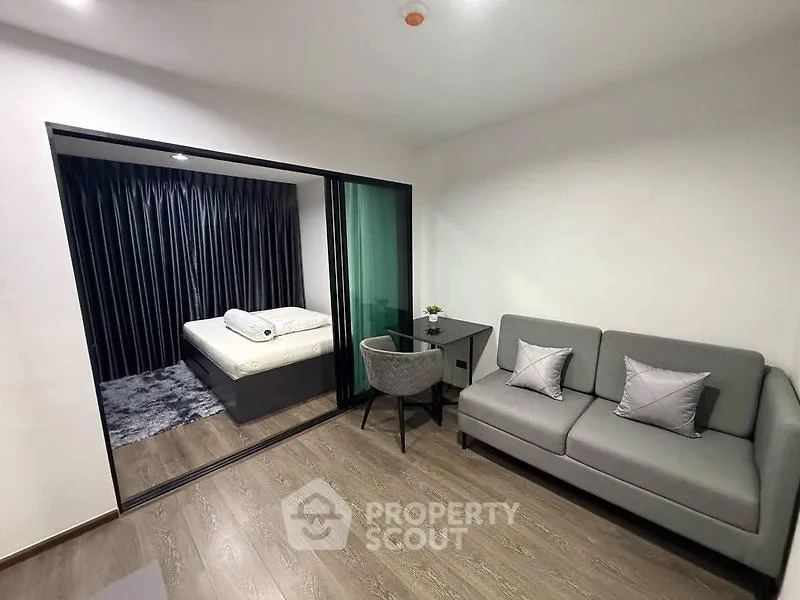Modern studio apartment with cozy living area and bedroom separated by glass partition.