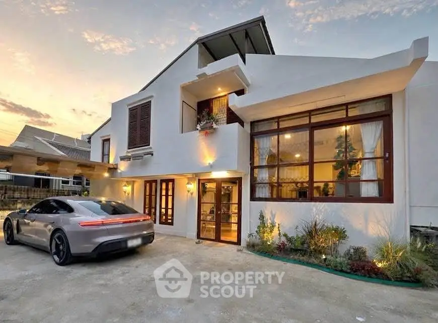 Stunning modern home with sleek architecture and luxury car in driveway at sunset.