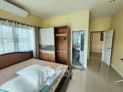 Spacious bedroom with modern design and ensuite bathroom, featuring large windows and ample natural light.