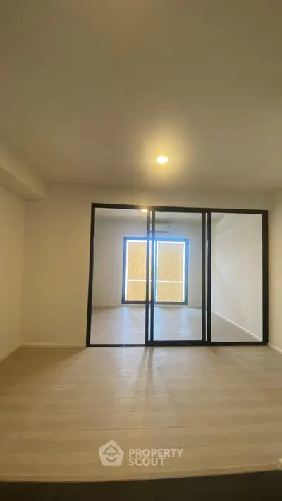 Spacious modern living room with glass partition and wooden flooring, ideal for contemporary living.