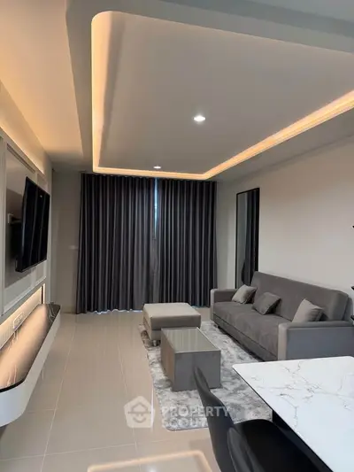 Modern living room with sleek design, featuring a gray sofa, stylish lighting, and a wall-mounted TV.