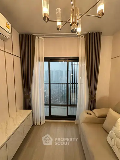 Stylish living room with modern chandelier and balcony view in a contemporary apartment.