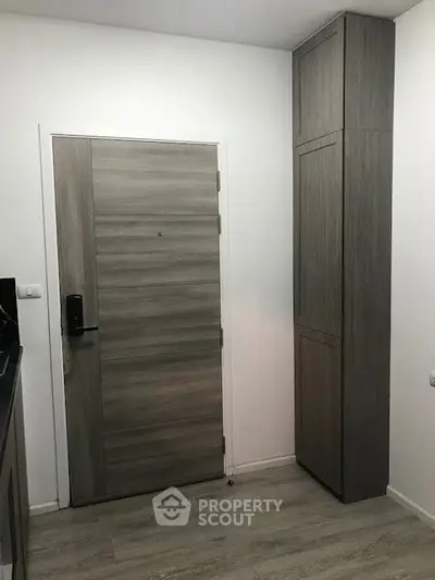 Modern apartment entrance with sleek wooden door and built-in storage.