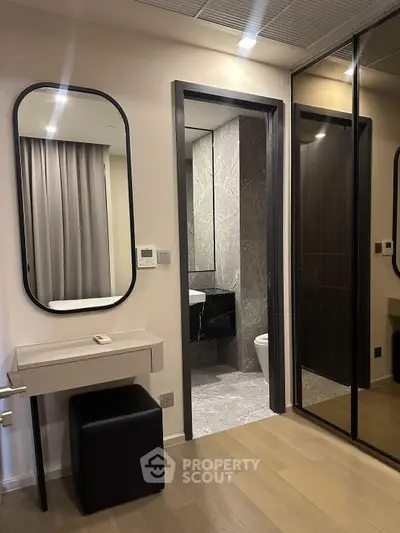 Modern interior with sleek bathroom and mirrored closet doors in a stylish apartment.