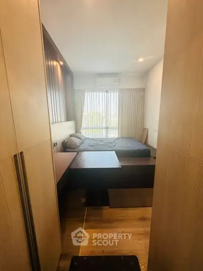 Cozy bedroom with large window and wooden accents, perfect for relaxation.