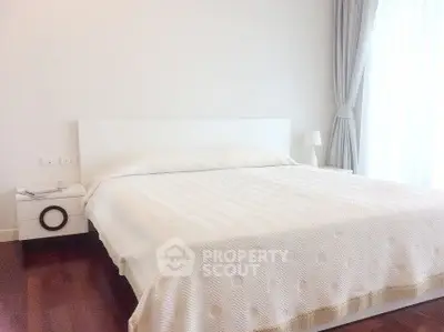 Spacious bedroom with modern decor and natural light, featuring a comfortable bed and elegant curtains.