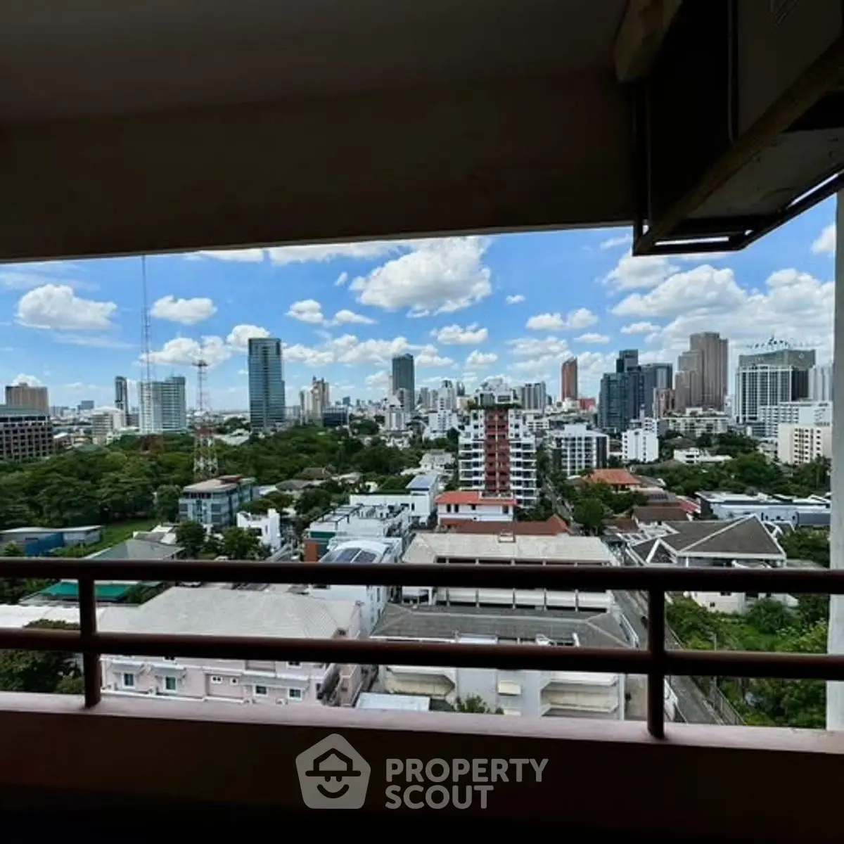 Stunning cityscape view from a high-rise balcony, showcasing urban skyline and lush greenery.