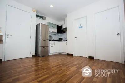 Modern kitchen with sleek appliances and wooden flooring in a compact apartment.