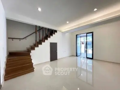 Spacious modern living room with sleek staircase and large glass doors