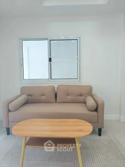 Modern living room with stylish beige sofa and wooden coffee table near a bright window.