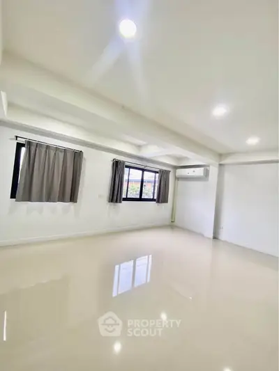Spacious unfurnished room with large windows and air conditioning, perfect for customization.