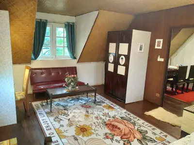 Charming attic living room with vintage decor and floral rug, featuring a cozy seating area and unique wooden accents.