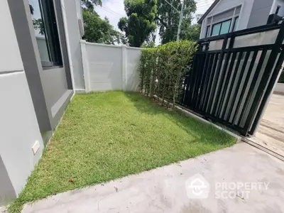 Charming small garden area with modern fence and lush greenery in a contemporary home setting.