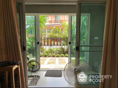 Charming garden view from cozy living room with sliding glass doors and lush greenery.