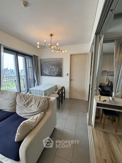 Modern living room with stylish chandelier and city view from large windows.