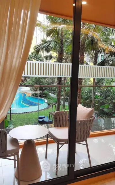 Luxurious balcony view overlooking a tropical garden and pool, perfect for relaxation and leisure.