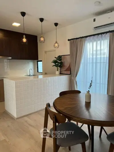 Modern kitchen with open layout and stylish dining area, featuring elegant lighting and natural light.