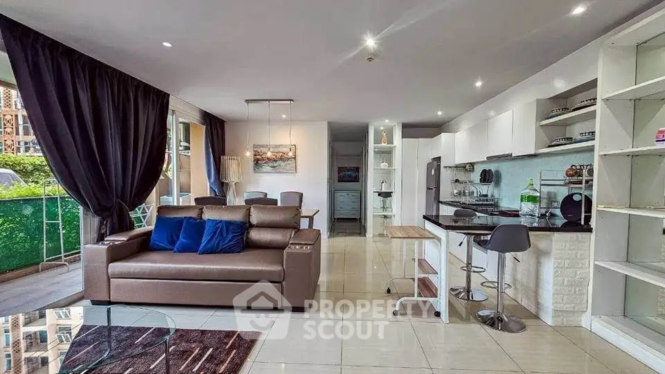 Spacious modern living room with open kitchen and balcony view, perfect for urban living.