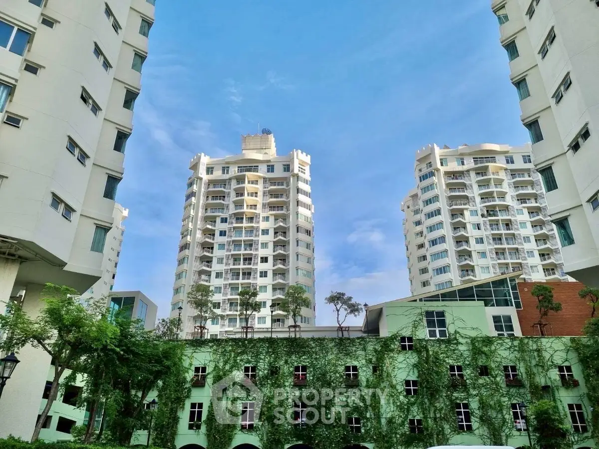 Stunning view of modern high-rise residential buildings with lush greenery and clear blue sky.
