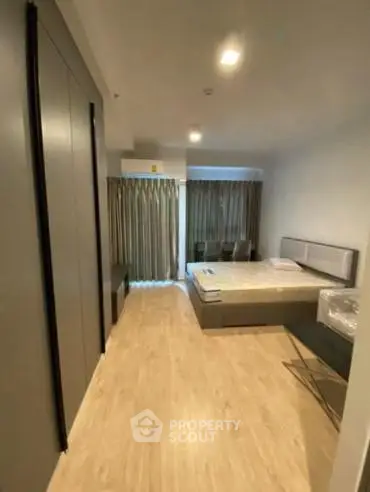 Modern bedroom with wooden flooring and large window for natural light