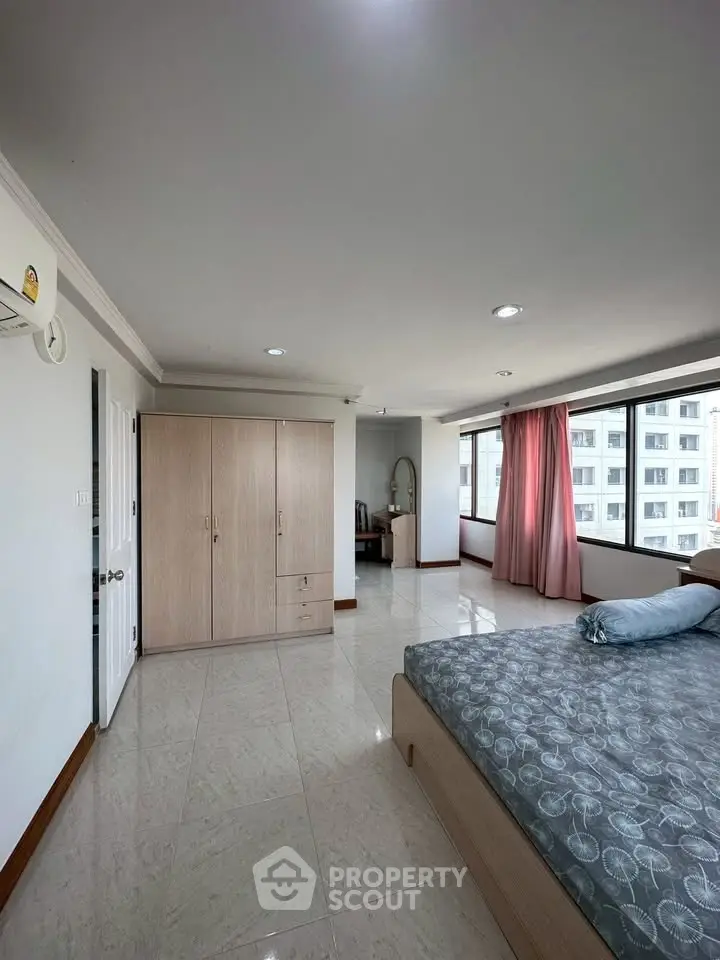 Spacious bedroom with large windows and ample natural light in modern apartment.