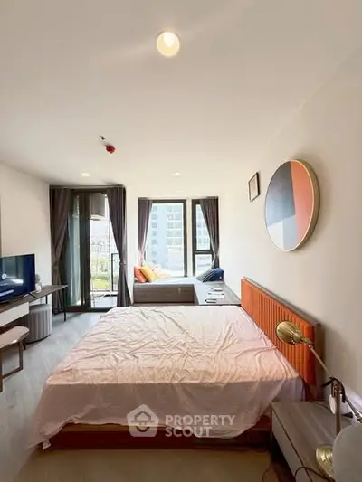 Spacious modern bedroom with large windows and stylish decor in a high-rise apartment.
