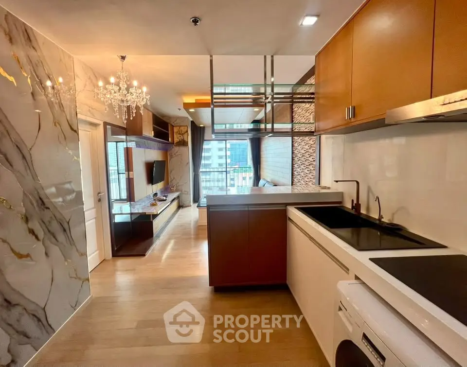 Luxurious modern apartment interior with open kitchen and elegant living area, featuring marble accents and chandelier.