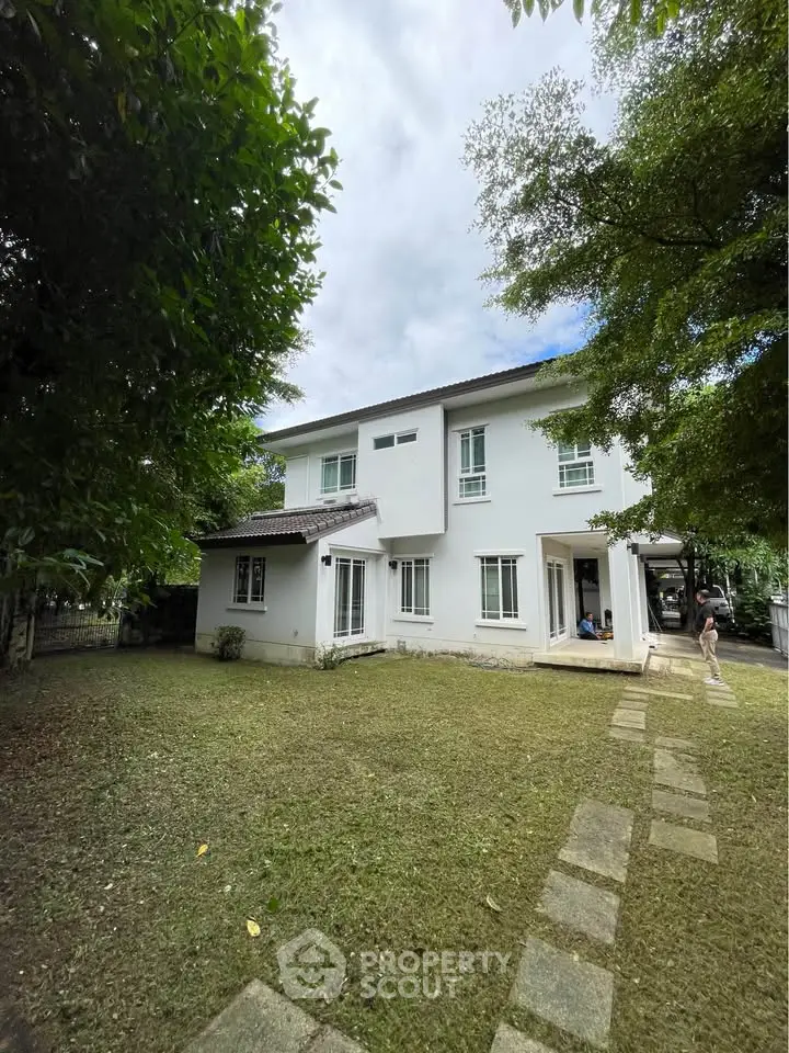 Charming two-story white house with spacious green lawn and pathway, perfect for family living.