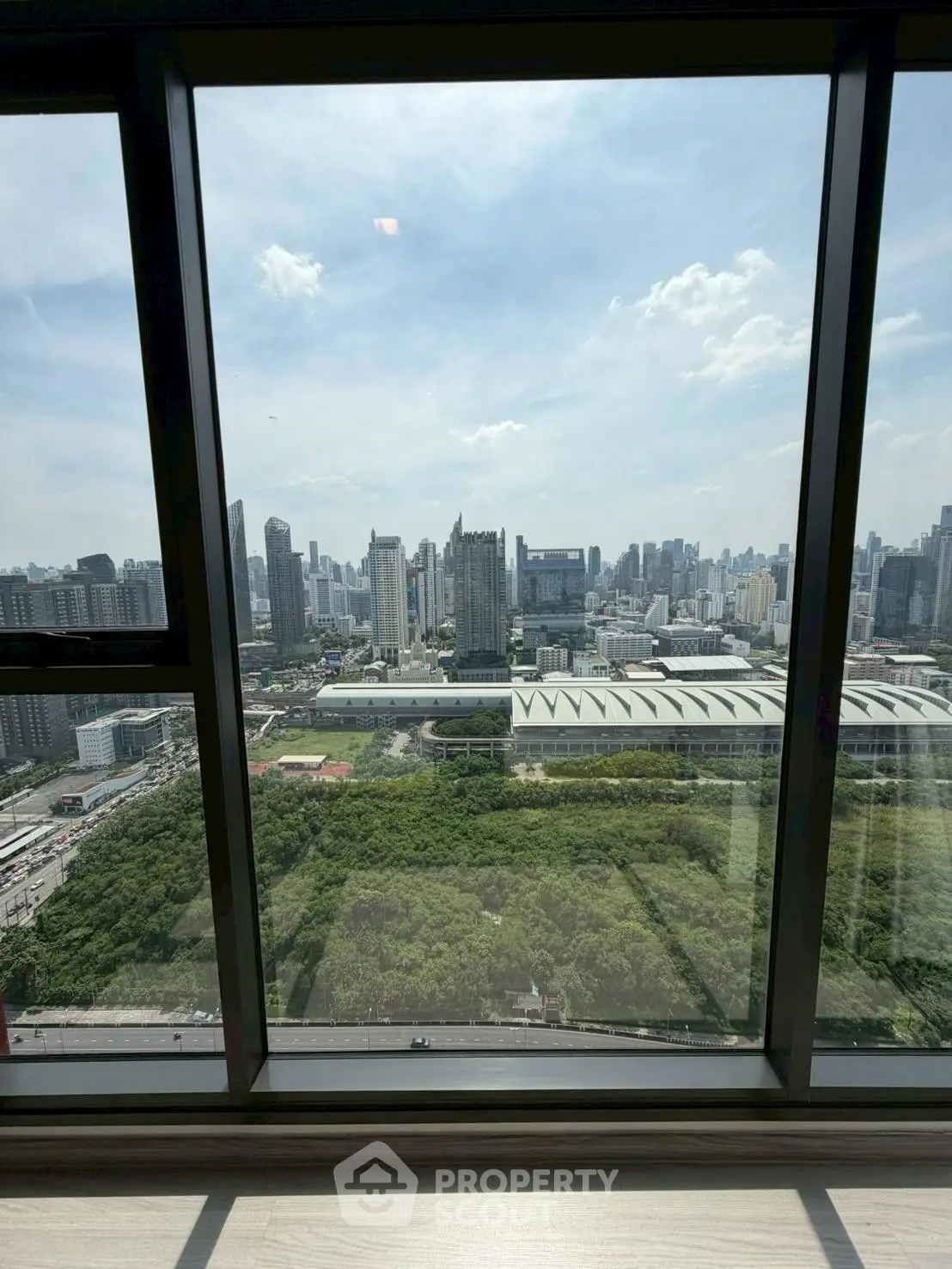 Stunning cityscape view from high-rise apartment window, showcasing urban skyline and greenery.