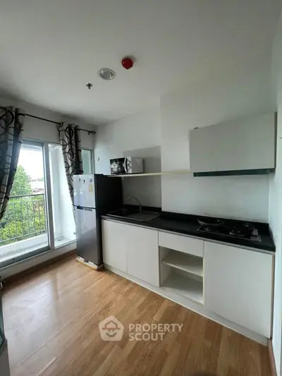Modern kitchen with sleek cabinets and balcony view, ideal for urban living.