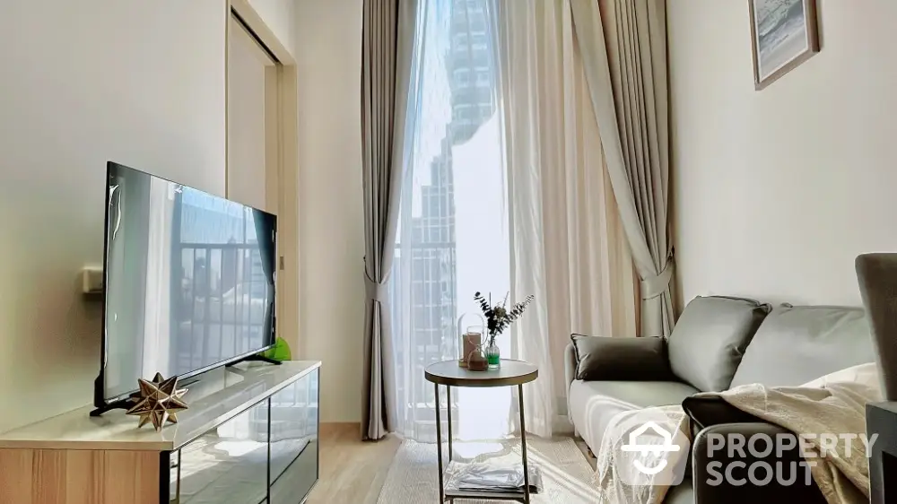 Modern living room with high ceilings and large window, featuring stylish furniture and natural light.