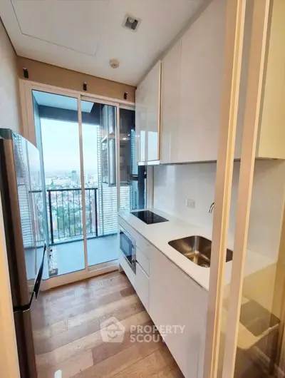 Modern kitchen with sleek cabinetry and balcony view, featuring a compact yet efficient layout.