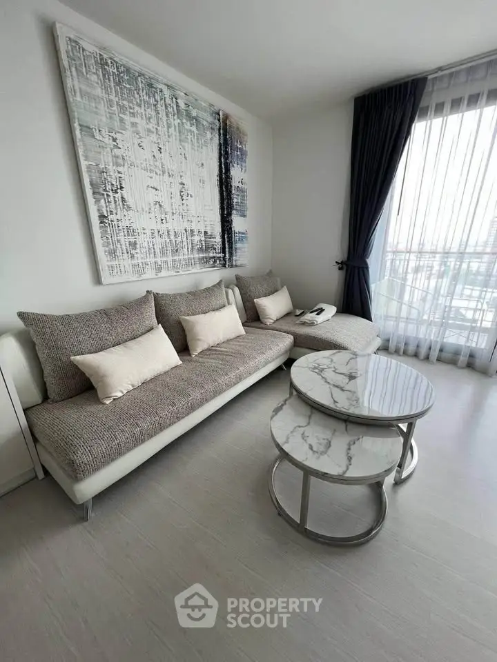Modern living room with stylish sofa and marble coffee tables, featuring large abstract wall art and floor-to-ceiling window.