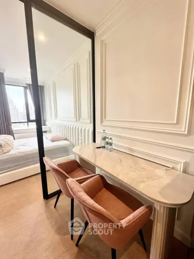 Elegant bedroom with stylish decor and city view, featuring a marble desk and plush chairs.