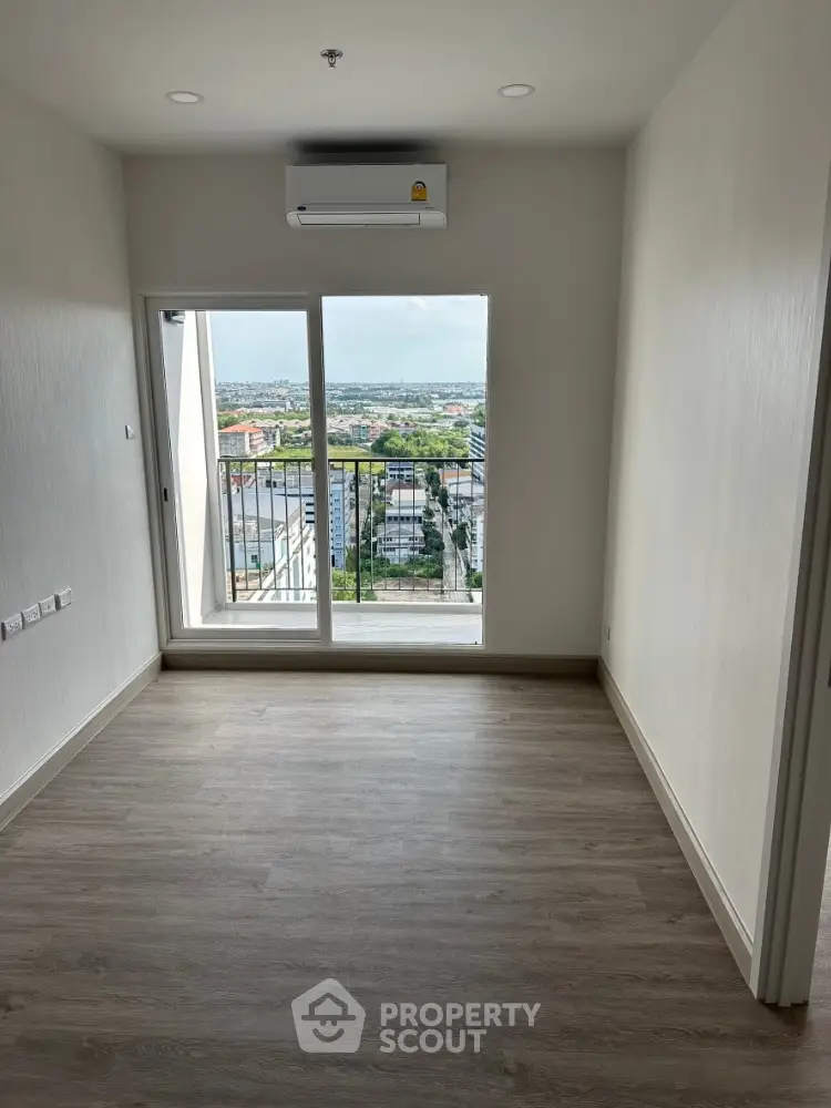 Spacious room with large window offering stunning city view and modern air conditioning unit.