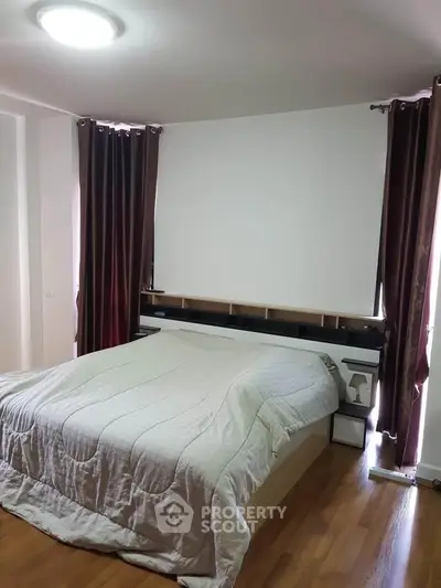 Spacious bedroom with elegant curtains and cozy bedding in modern apartment.