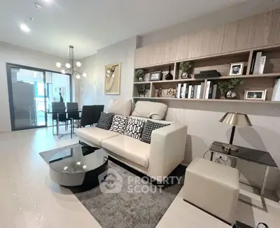 Modern living room with stylish decor and open dining area, featuring elegant lighting and contemporary furniture.