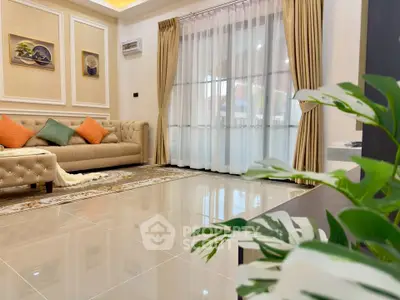 Elegant living room with plush sofa, decorative pillows, and large window draped with curtains.
