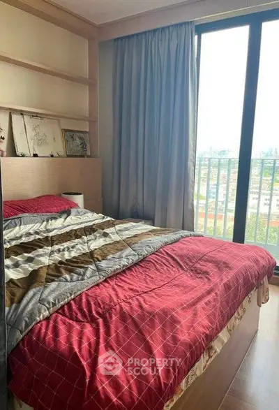 Cozy bedroom with large window and city view, featuring modern decor and comfortable bedding.