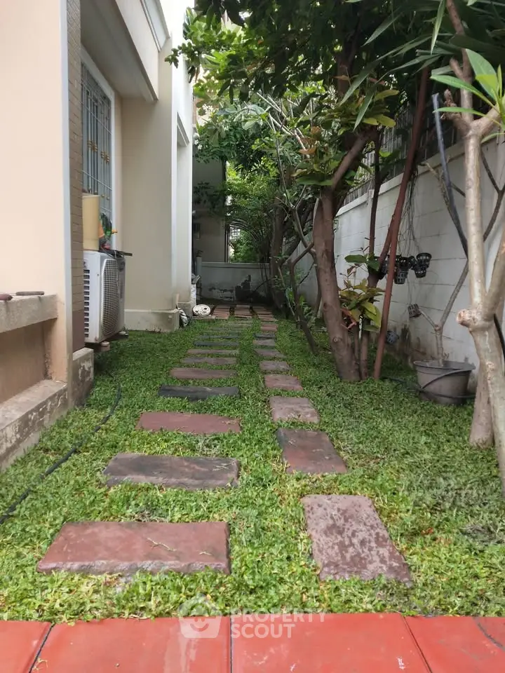 Charming garden path with lush greenery and stepping stones in a cozy backyard setting.