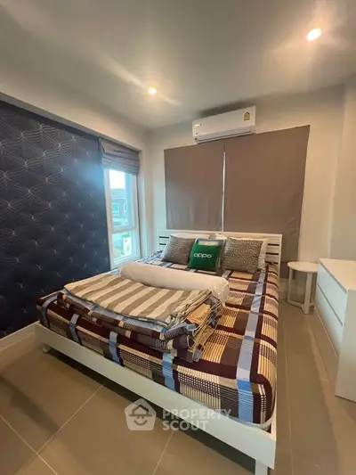 Modern bedroom with stylish decor and ample natural light, featuring a comfortable bed and air conditioning.