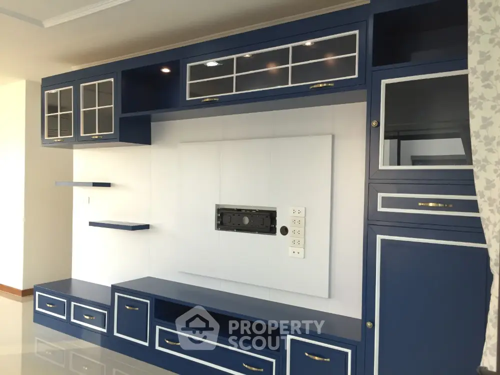 Modern living room with stylish blue built-in entertainment unit and elegant cabinetry.