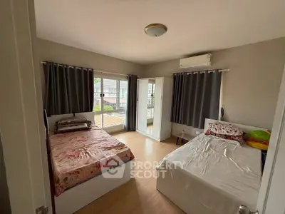 Spacious bedroom with two beds, large windows, and modern decor in a well-lit apartment.
