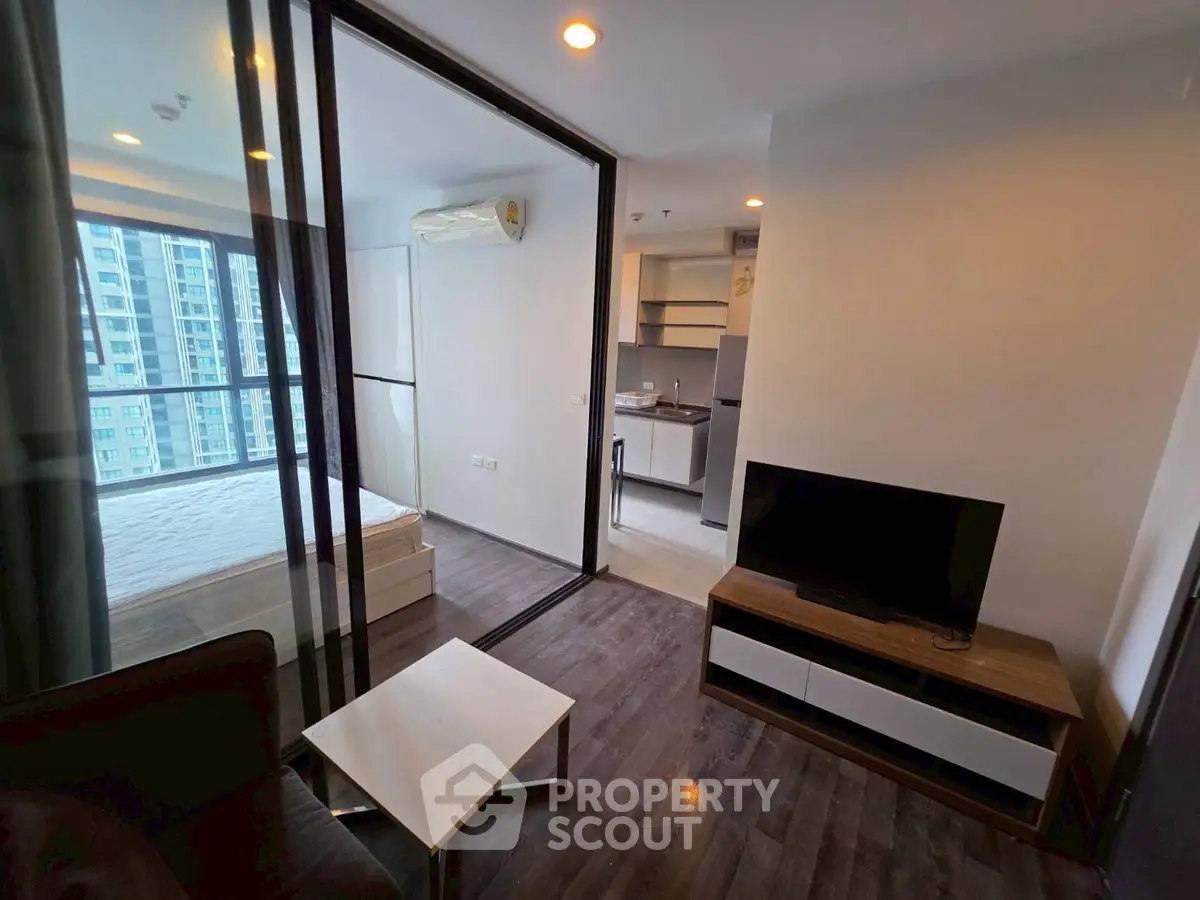 Modern condo interior with open layout, featuring a cozy living area and a glimpse of the bedroom.