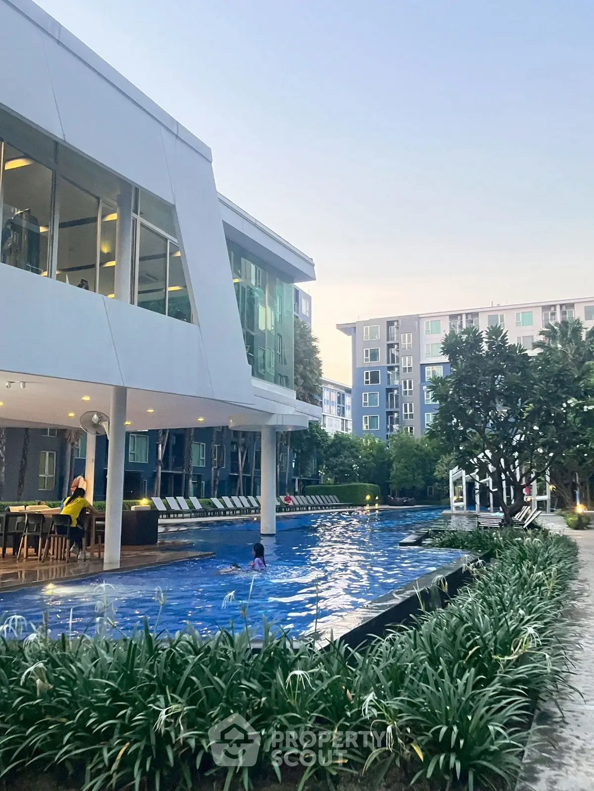 Modern apartment complex with pool and lush greenery, perfect for urban living.