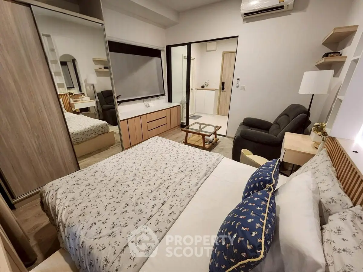 Cozy bedroom with modern decor, mirrored wardrobe, and comfortable seating area.