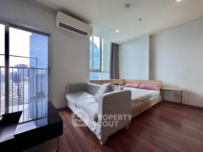 Modern bedroom with city view, featuring sleek wooden flooring and contemporary furniture.