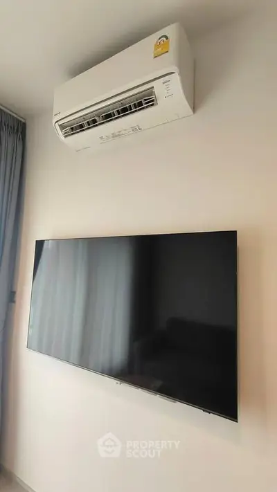 Modern living room with wall-mounted TV and air conditioning unit, perfect for comfortable living.